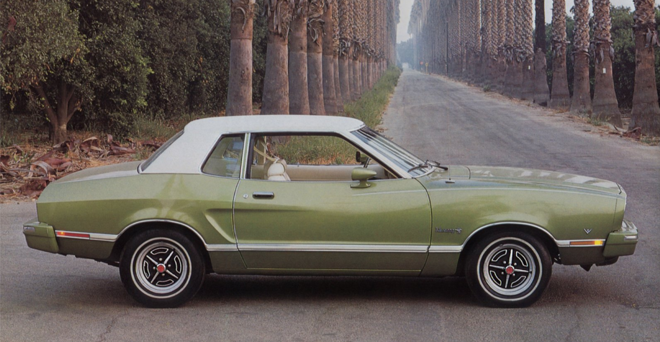 Olive green 1975 Ford Mustang II on road near palm trees