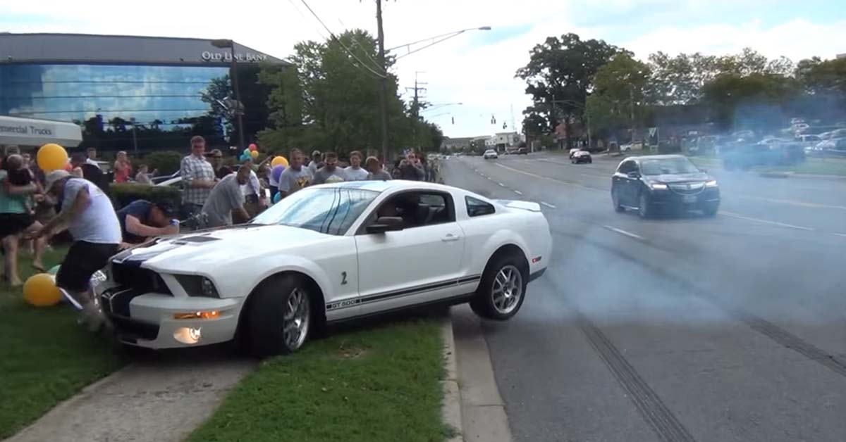 Fifth generation white Mustang crashing into a crowd