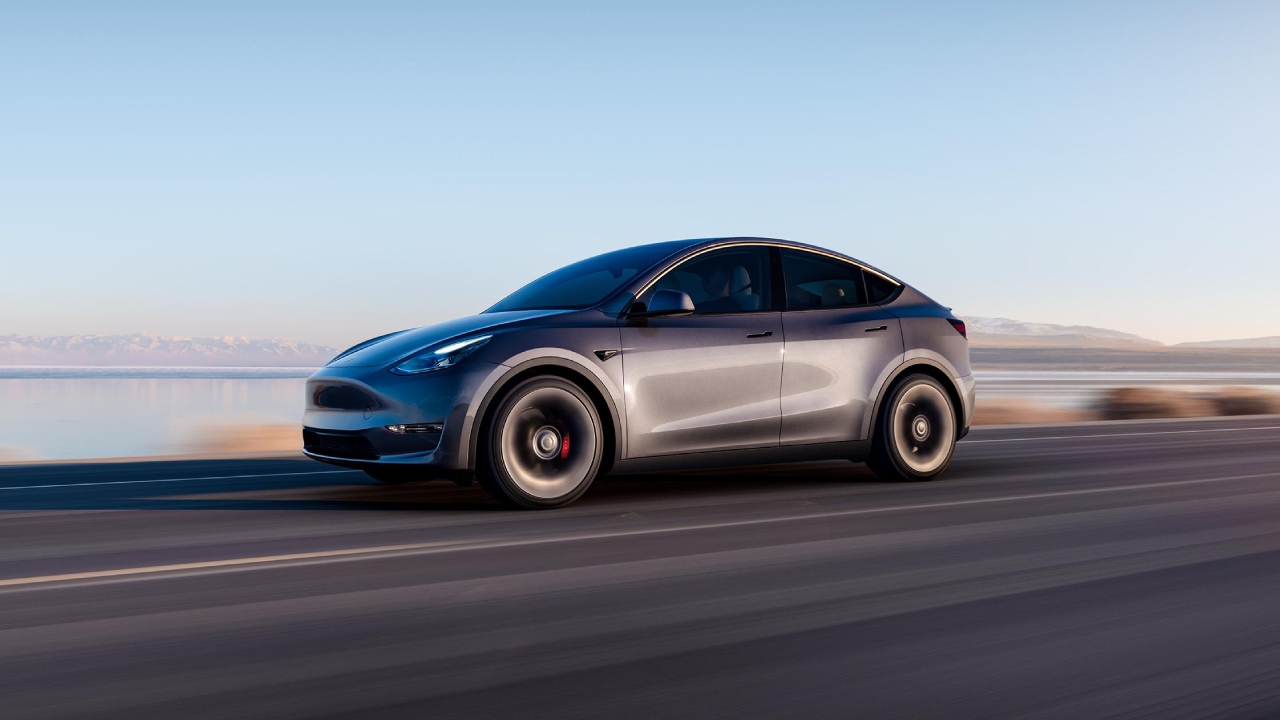 Tesla Model Y accelerating down an empty road with a lake in the background