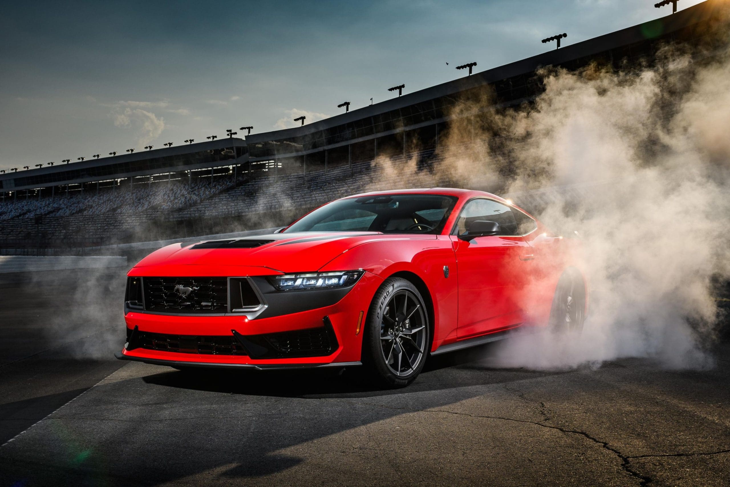 red mustang dark horse doing burnout on race track